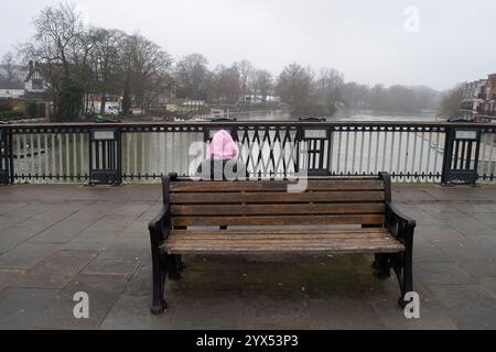 Windsor, Berkshire, Großbritannien. Dezember 2024. Ein düsterer Tag in Windsor, Berkshire, sitzt als Mädchen auf einer Bank mit Blick auf die Themse. Kredit: Maureen McLean/Alamy Stockfoto
