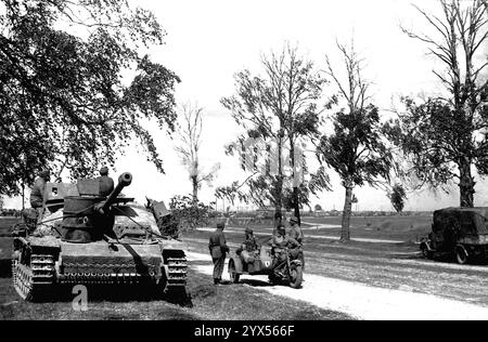 Russland Juli 1944: Neben der Start- und Landebahn Moskau-Minsk während des deutschen Rückzugs in der Nähe der russischen Operation Bagration im Bereich des Heeresgruppenzentrums. Ein Motorrad auf der Straße, daneben in einer Allee von Bäumen, ein Sturmgewehr III, der keine Munition mehr hat. Im Hintergrund verstopfte die Landebahn mit deutschen Militärfahrzeugen. [Automatisierte Übersetzung] Stockfoto