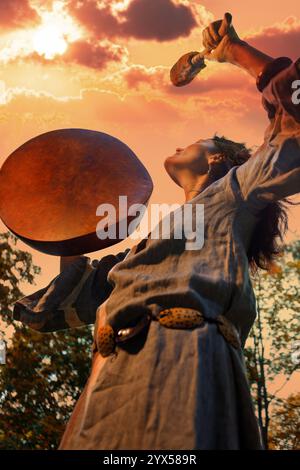 Die Schamanin führt ein Ritual mit einem Tambourin bei Sonnenuntergang im Wald durch. Schamanisches Ritual. Ethnische Traditionen Stockfoto