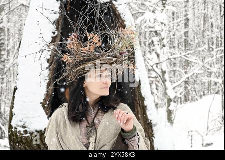 Porträt einer schönen Frau mit einem Zweigkranz auf dem Kopf im Winterwald Stockfoto