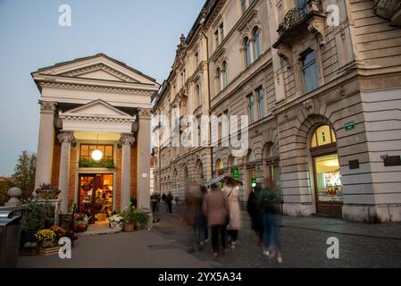 Ljubljana, Slowenien, Oktober 30 2024: Menschen, die in der Abenddämmerung auf dem preseren Platz im Stadtzentrum von ljubljana spazieren, mit Blumenladen im Vordergrund Stockfoto