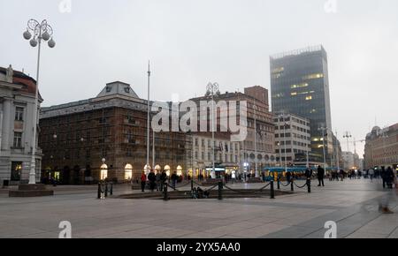 Leute, die spazieren gehen und genießen Ban jelacic Platz in zagreb, kroatien, mit einer Straßenbahn, die in der Abenddämmerung vorbeifährt Stockfoto