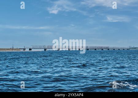 Kaiserbrücke, kombinierte Straßen- und Eisenbahnbrücke über die Wolga, Kuibyschew Reservoir, Uljanowsk, Russland. Der Zug fährt über die Brücke. Blick vom Wasser. Stockfoto