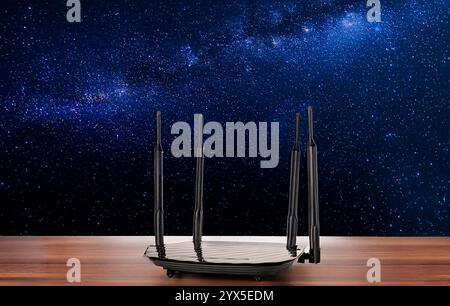 Ein Router für die WLAN-Verteilung auf einem Holztisch, Nahaufnahme, vor dem Hintergrund eines Sternenhimmels. Stockfoto