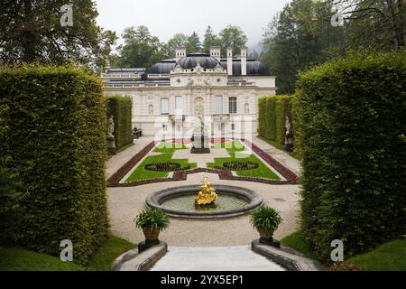 Hochwinkelblick auf Parterre mit Grenzen und Wasserbrunnen, die von Laubbaumhecken im formellen Garten des Linderhofs im Spätsommer begrenzt werden. Stockfoto