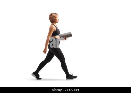 Asiatische Frau in Sportbekleidung, die eine Trainingsmatte trägt und isoliert auf weißem Hintergrund läuft Stockfoto