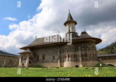 Das Bild zeigt ein historisches rumänisches orthodoxes Kloster Voroneț mit komplizierten Fresken und lebendigen Wandmalereien und Holzdächern. Stockfoto