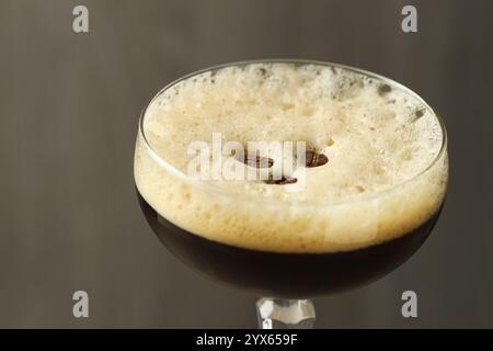 Köstlicher Espresso-Martini mit Kaffeebohnen im Glas auf verschwommenem Hintergrund, Nahaufnahme Stockfoto