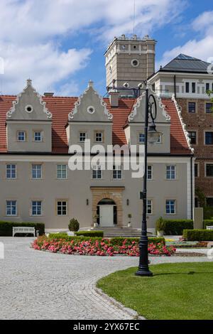 Elegantes historisches Gebäude mit dekorativen Giebeldächern, Kopfsteinpflasterweg, blühenden Blumen und klassischer Architektur unter einem leuchtend blauen Himmel Stockfoto