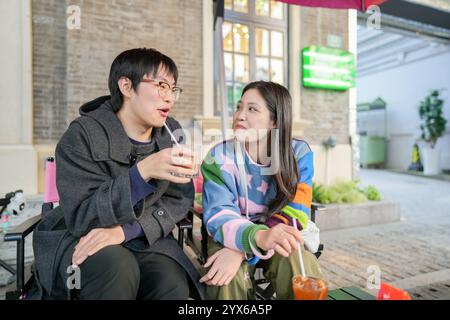 Ein junges chinesisches Paar im Alter von 20 Jahren trinkt Kaffee oder Tee auf der Terrasse eines Cafés im Bezirk Hongkou, Shanghai, Volksrepublik China Stockfoto