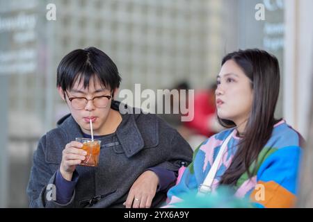 Ein junges chinesisches Paar im Alter von 20 Jahren trinkt Kaffee oder Tee auf der Terrasse eines Cafés im Bezirk Hongkou, Shanghai, Volksrepublik China Stockfoto