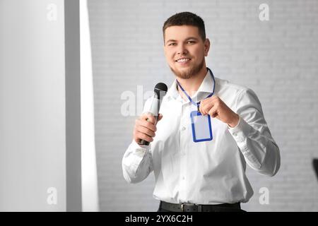Männlicher Reporter mit Mikrofon und leerem Namensschild im Büro Stockfoto