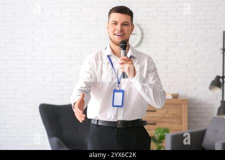 Männlicher Reporter mit Mikrofon und leerem Namensschild, der die Hand zum Handshake im Studio verlängert Stockfoto