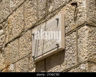 Korcula, Kroatien - 30. Juni 2024: Namensschild der Depolo-Gasse an der alten Steinmauer Stockfoto