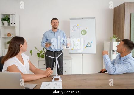 Männlicher Ingenieur mit Windkraftanlagenmodell, der seine Kollegen im Büro vorstellt Stockfoto