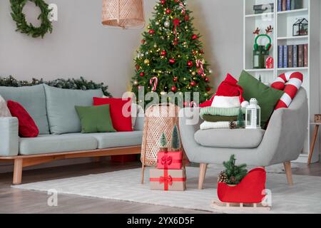 Stapel Winterkleidung mit Weihnachtsdekoration und Geschenkboxen auf dem Sessel zu Hause Stockfoto