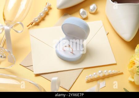 Verlobungsring mit Umschlägen und Brautaccessoires auf gelbem Hintergrund Stockfoto