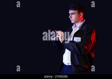 Männlicher FBI-Agent mit Fernglas auf dunklem Hintergrund Stockfoto