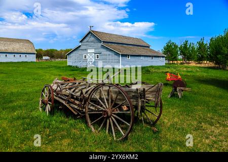 Ein Holzwagen sitzt auf einem Feld neben einer Scheune. Die Scheune ist alt und der Wagen ist verrostet. Die Szene ist friedlich und ruhig, mit den einzigen Geräuschen Stockfoto