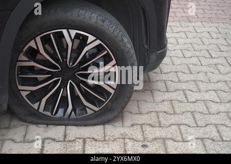 Nahaufnahme des flachen Reifens auf befestigtem Boden, die die Situation der Auto-Reparaturen darstellt Stockfoto