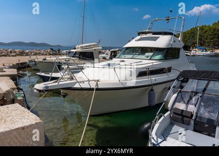 Elegantes weißes Motorboot vor Anker im ruhigen Hafen mit üppigem Grün und Villen am Hügel unter klarem blauem Himmel an einem hellen sonnigen Tag. Konzept Stockfoto