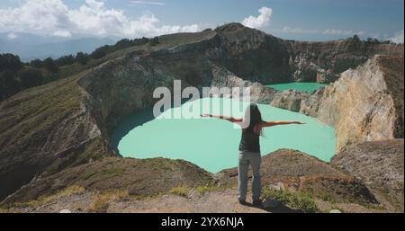 Frau genießt den Rand des Vulkangebirges. Vulkanischer Kelimutu-blauer Kratersee. Reiseziel. Wunderschöne wilde Landschaft. Weibliche Touristin im Sommerurlaub. Lifestyle-Urlaubskonzept. Rückansicht Stockfoto