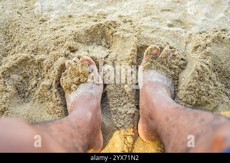 Man Füße am Sandstrand und mit Sand gefüllt. Konzentrieren Sie sich auf Füße, Geräusche, Exposition usw. Stockfoto