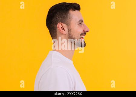 Seitenprofil eines lächelnden Mannes in einem weißen T-Shirt auf gelbem Hintergrund Stockfoto