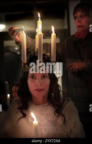 London, Großbritannien. Dezember 2024. Sankta-Lucia-Feiern des schwedischen Chors Norrsång East London in der St. Mary’s Church in Walthamstow. Alma Fridell Crawshaw hat ihre Kerzenkrone angezündet. Als Symbol der heiligen Lucy leitet sie die Feier der Sankta Lucia, basierend auf der Tapferkeit und dem Martyrium eines jungen sizilianischen Mädchens, der heiligen Lucy (Lucia von Syrakus 283–304). Guy Corbishley/Alamy Live News Stockfoto