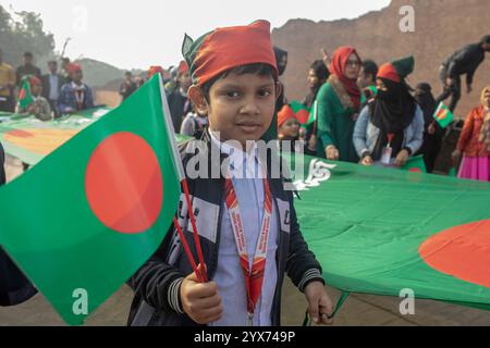 Dhaka, Bangladesch. Dezember 2024. Ein Junge hält am Gedenktag der Märtyrer-Intellektuellen eine Flagge von Bangladesch. Am Gedenktag der Märtyrer-Intellektuellen in Bangladesch werden zahlreiche bengalische Intellektuelle geehrt, die während des Befreiungskrieges in Bangladesch 1971 tragischerweise ihr Leben verloren haben. Diese Intellektuellen wurden von der pakistanischen Armee und ihren Verbündeten im gesamten ehemaligen Ostpakistan absichtlich angegriffen und brutal getötet, um die aufstrebende Nation durch die Ausrottung ihrer talentierten und intellektuellen Individuen zu untergraben. Quelle: SOPA Images Limited/Alamy Live News Stockfoto