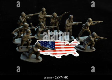 Armeefiguren rund um die USA-Kartenflagge auf schwarzem Hintergrund. Verteidigungskonzept. Stockfoto