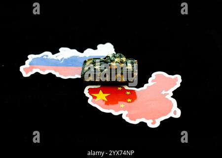 Miniatur-Spielzeugtank auf Karten von Russland und China mit Flaggen Farben und Design. Geopolitisches Bündniskonzept. Stockfoto