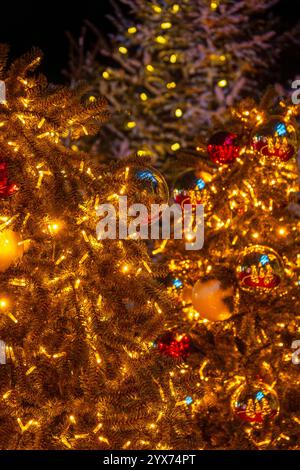 Beleuchtete Weihnachtstannen mit dekorativer Weihnachtskugeldekoration und warmer Beleuchtung. Stockfoto