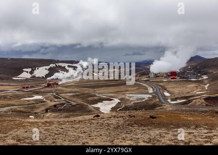 Das geothermische Kraftwerk Krafla im Vulkangebiet Myvatn in Island, Landschaftsblick mit gewundenen Straßen und Bergen im Hintergrund. Stockfoto