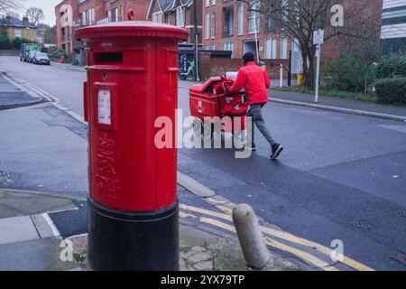 London, Großbritannien. 14. Dezember 2024 Ein Postbote, der außerhalb des Sortierbüros von Wimbledon Lieferungen tätigt. Royal Mail wurde von der Aufsichtsbehörde Ofcom mit einer Geldstrafe von 10,5 Mio. £ belegt, weil sie die Zustellziele für Post erster und zweiter Klasse nicht erfüllt hat. Royal Mail ist Gegenstand eines Übernahmeangebots des tschechischen Milliardärs Daniel Kretinsky. .Credit.Amer Ghazzal/Alamy Live News Stockfoto