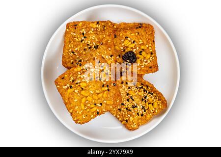 Ansicht von oben auf quadratische Riegel von knusprigem hausgemachtem Mehrkornreis-Cracker in weißer Keramikschale isoliert auf weißem Hintergrund mit Schneidepfad. Stockfoto