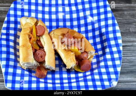 Teilweise geschnittenes langes Brötchen mit gegrillter Rinderwurst, genannt wiener (Wiener Wurst) und frankfurter Frank, mit Zwiebelscheiben und buntem b Stockfoto