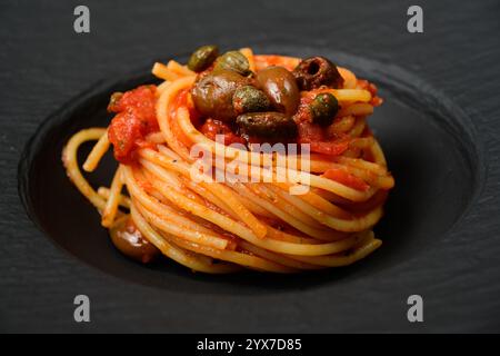 Spaghetti alla puttanesca italienische Pasta mit einer scharfen Tomatensauce mit schwarzen Oliven und Kapern Stockfoto
