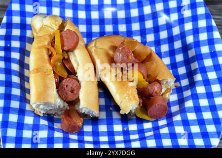 Teilweise geschnittenes langes Brötchen mit gegrillter Rinderwurst, genannt wiener (Wiener Wurst) und frankfurter Frank, mit Zwiebelscheiben und buntem b Stockfoto