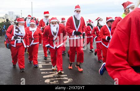 Brighton UK 14. Dezember 2024 - Teilnehmer an diesem Jahr Brighton Santa Dash entlang Hove Seafront sammeln Geld für die Rockinghorse Children’s Charity an einem kühlen, langweiligen Morgen entlang der Südküste : Credit Simon Dack / Alamy Live News Stockfoto