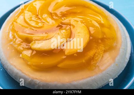 Pfirsich, Gelee Dessert oder Kuchen. Hausgemachter Käsekuchen mit Pfirsichen aus der Dose auf einem blauen Teller. Hochwertige Fotos Stockfoto