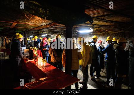 Goslar, Deutschland. Dezember 2024. Besucher stehen an einem Glühweinstand im „Roeder-Stollen“ am Weihnachtsmarkt im Rammelsberg-Weltkulturerbe. Der Weihnachtsmarkt im historischen UNESCO-Weltkulturerbe Rammelsberg findet am dritten Adventswochenende über- und unterirdisch statt. Früher wurde in der Mine Erz abgebaut, um NE-Metalle zu gewinnen. Quelle: Swen Pförtner/dpa/Alamy Live News Stockfoto