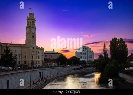 Turm des Rathauses von Oradea am Ufer des Flusses Crisu Repede. Sonnenuntergang in Oradea, Rumänien Stockfoto