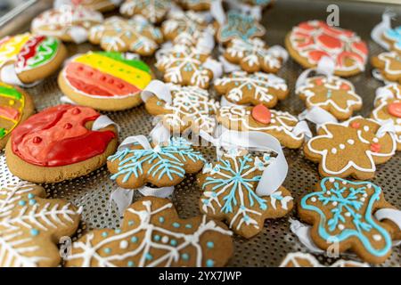Neujahrs- oder Weihnachtskekse in Form von Schneeflocken und Weihnachtskugeln mit Bändern auf dem Produktionstisch. Lebkuchenspielzeug für die CH Stockfoto