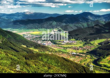 Stadt Ruzomberok vom Hügel Hrdos (Ostre) im Nationalpark Mala Fatra in der Slowakei. Niedrige Tatra Berge im Hintergrund Stockfoto