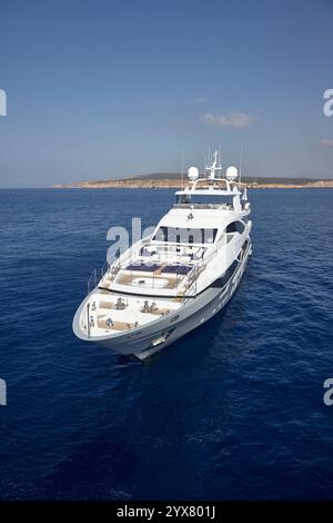 Luxuriöse Motoryacht in Anchor im sonnendurchfluteten blauen Ozean in der Nähe der malerischen Küste Stockfoto