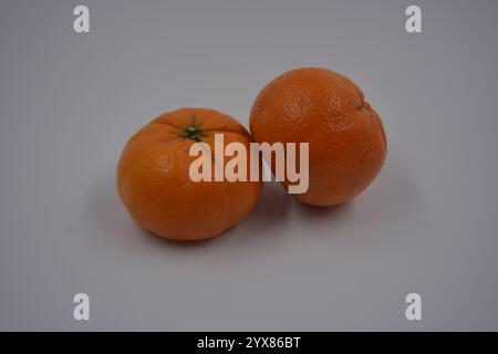 Gesundes, gesundes Essen, Essen, frisches Obst. Wunderschöne zwei ganze reife Orangenmandarinen befinden sich auf einem weißen Kunststoffhintergrund. Stockfoto