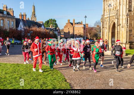 Einige der mehr als 600 Santas passieren die Kathedrale, während sie den Santa Fun Run laufen, der von Rotary International am 14./12/2024 in Gloucester, England U, organisiert wurde Stockfoto