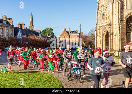 Einige der mehr als 600 Santas passieren die Kathedrale, während sie den Santa Fun Run laufen, der von Rotary International am 14./12/2024 in Gloucester, England U, organisiert wurde Stockfoto