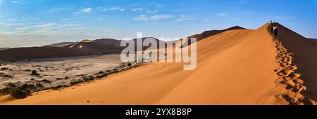 Sossusvlei ist von einem Dünenkamm aus zu sehen. Leute, die den Kamm entlang laufen, hinterlassen Spuren. Sesriem-Nationalpark, Namibia, Afrika. Stockfoto